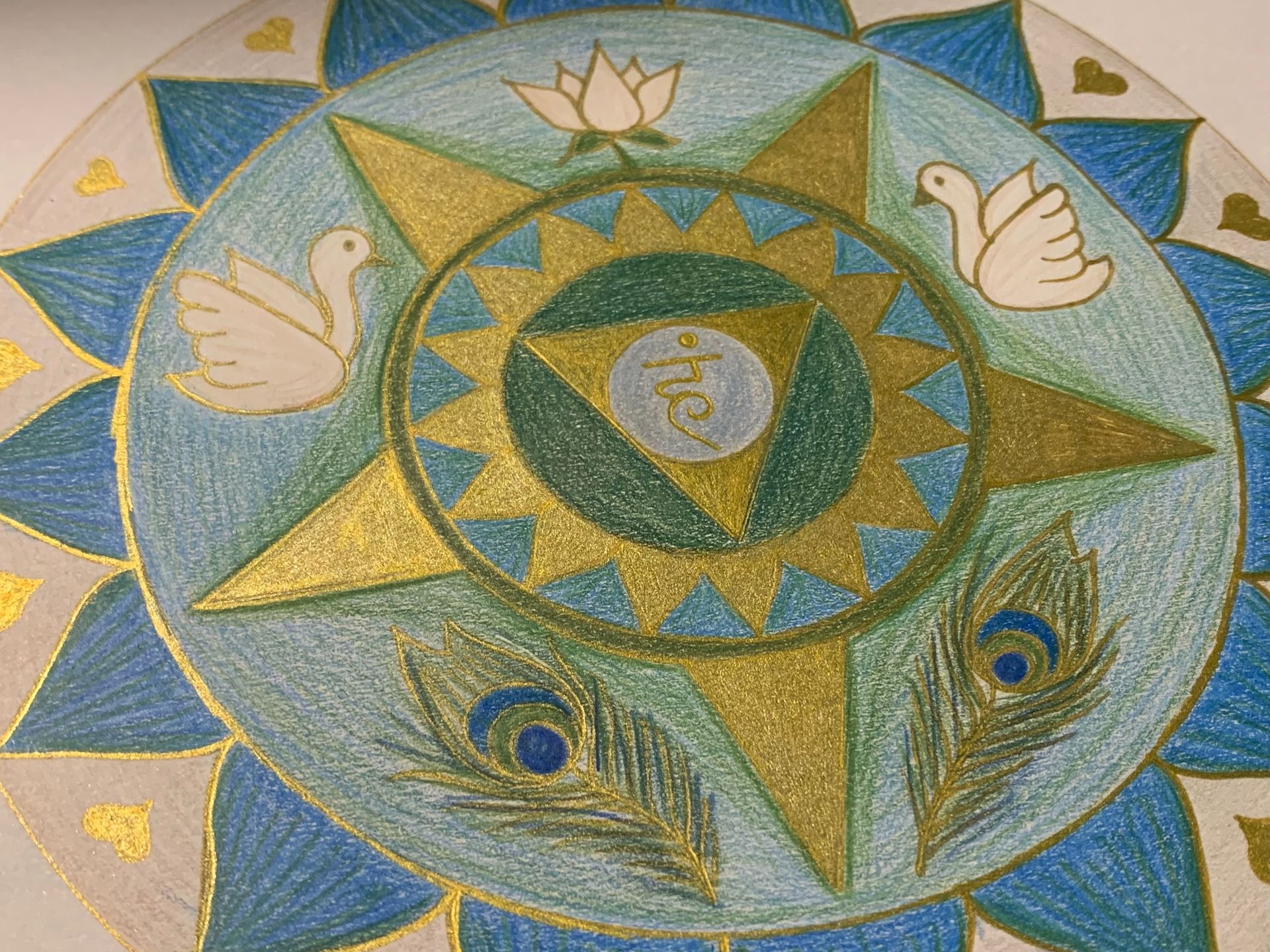 Colorful mandala with gold star, blue and teal details, doves, lotus, and peacock feathers.