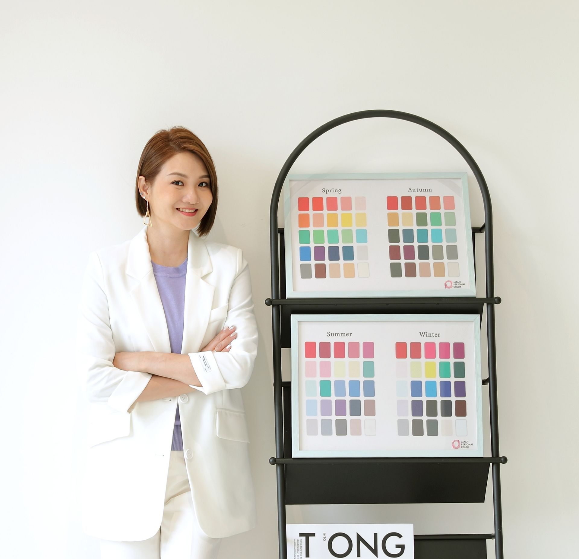 一位穿著白色西裝的女子站在雜誌架旁。