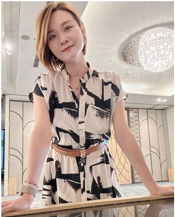 一位穿著洋裝的女人站在鏡子前。