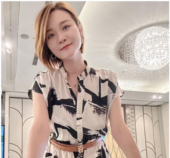 一位穿著洋裝的女人站在鏡子前。