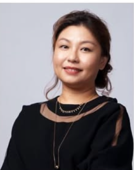 一位身穿黑色洋裝、戴著金項鍊的女子對著鏡頭微笑。