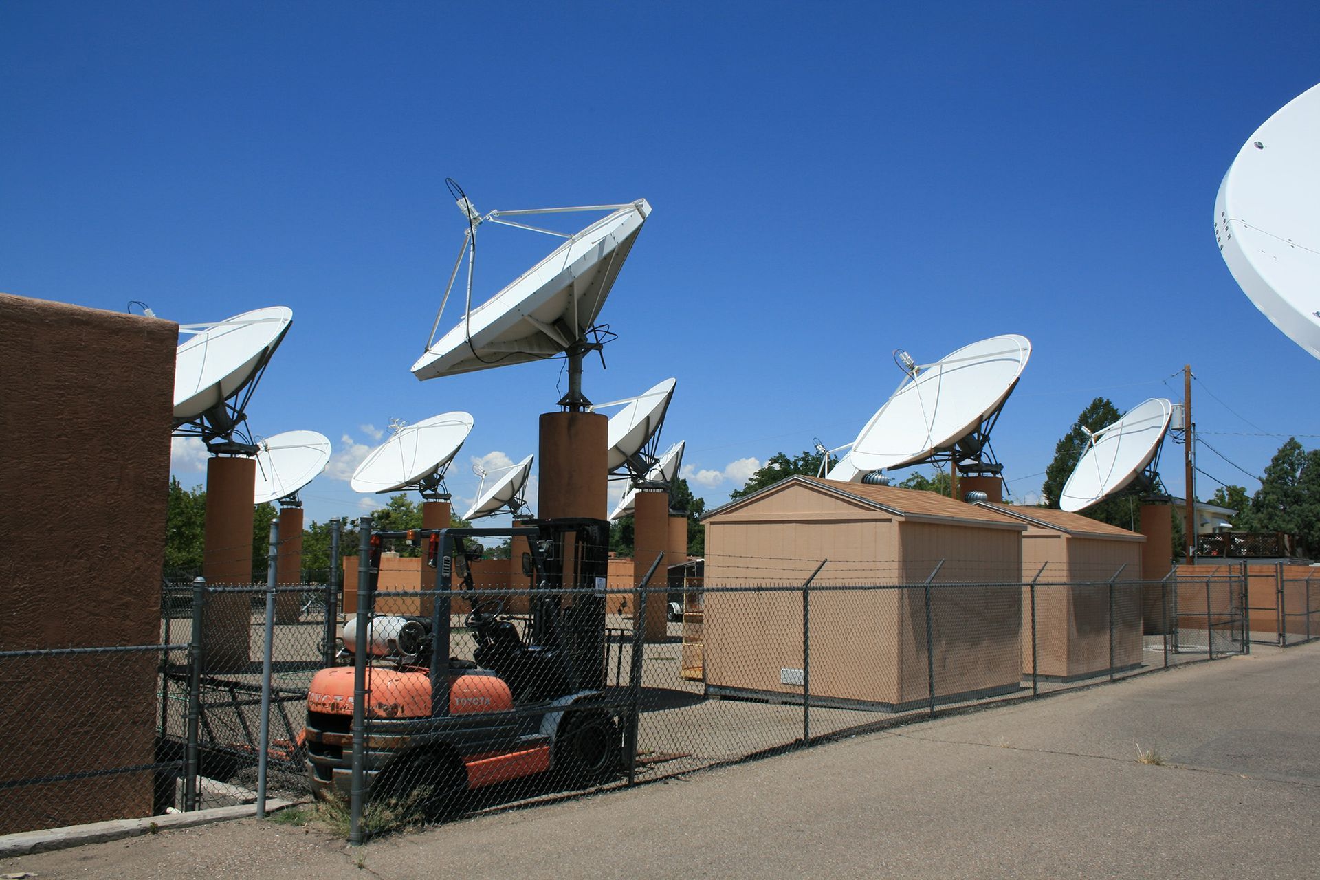 A forklift is parked in front of a bunch of satellite dishes