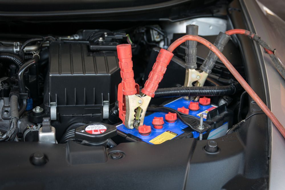 A Car Battery Is Being Charged With Jumper Cables — Too Ezy Auto Electrics In Townsville, QLD