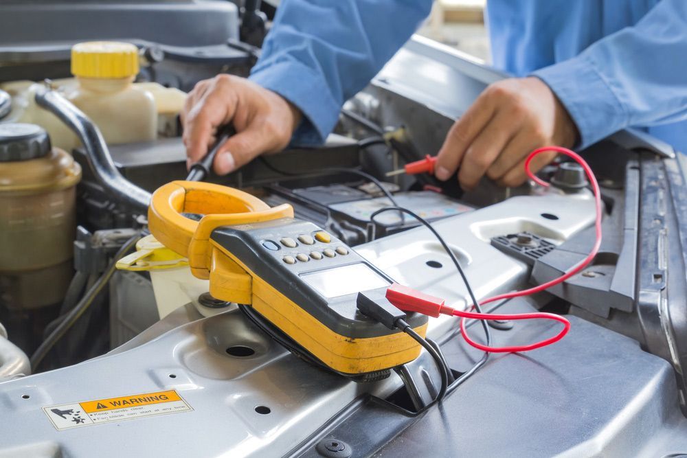 A Man Is Working On A Car With A Voltmeter — Too Ezy Auto Electrics In Townsville, QLD