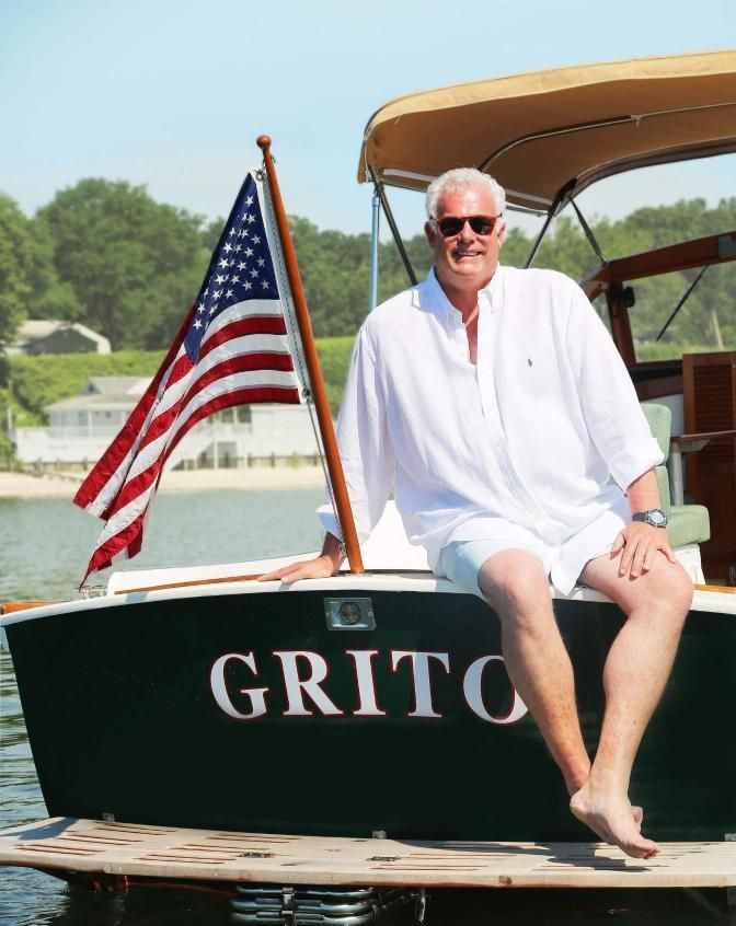 A top realtor in St. James, Thomas McCloskey, sits on the back of a boat that says grito