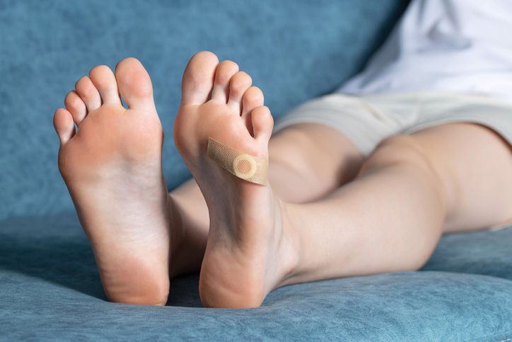 A person is laying on a couch with a patch on their foot.