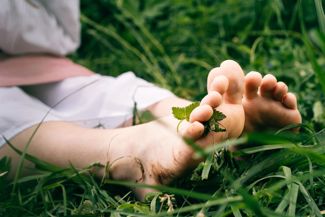 A person is laying in the grass with their feet in the grass.