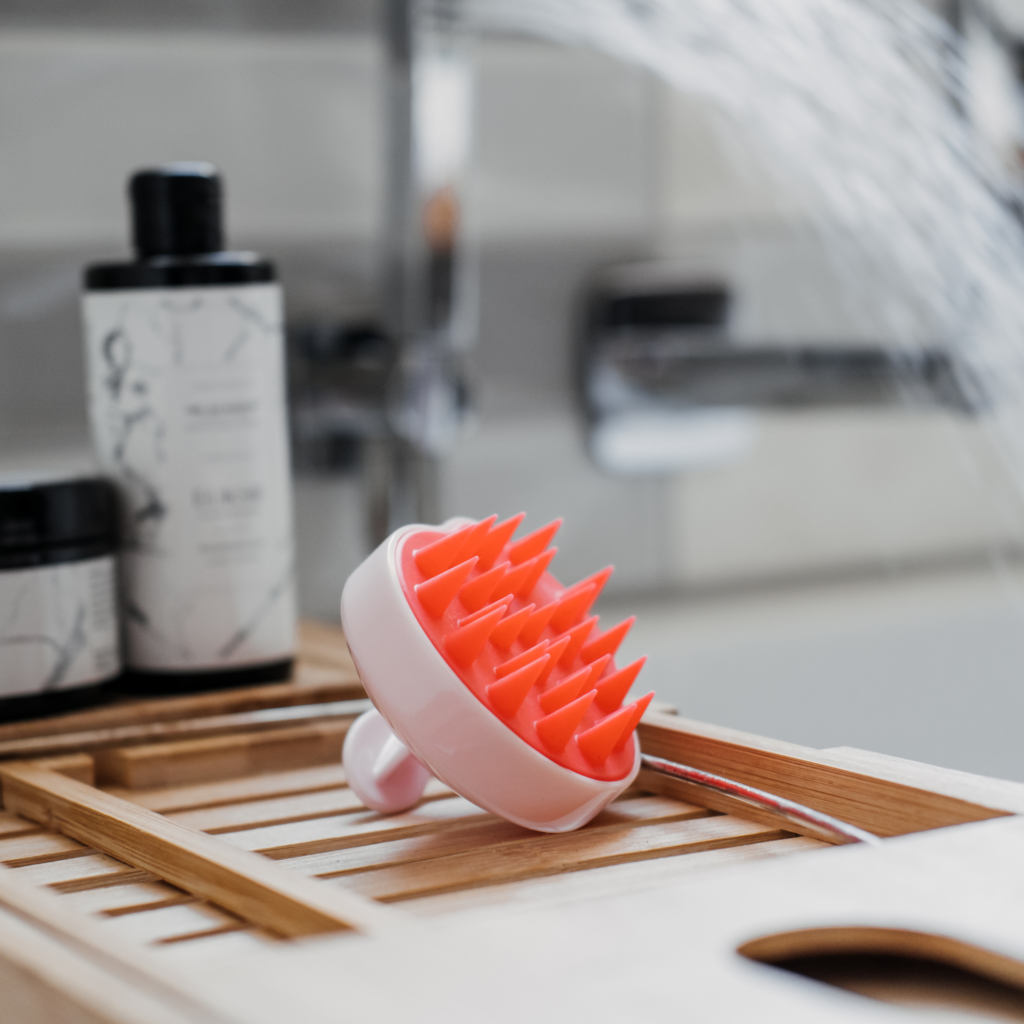 A pink hair brush is sitting on a wooden tray.