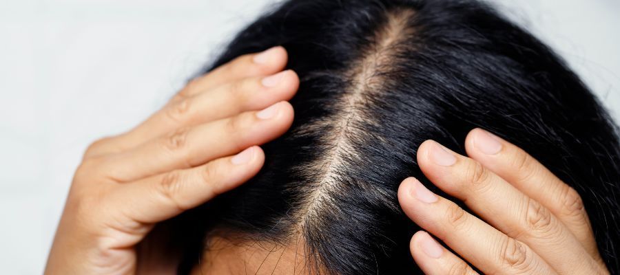 A woman is touching her hair with her hands.