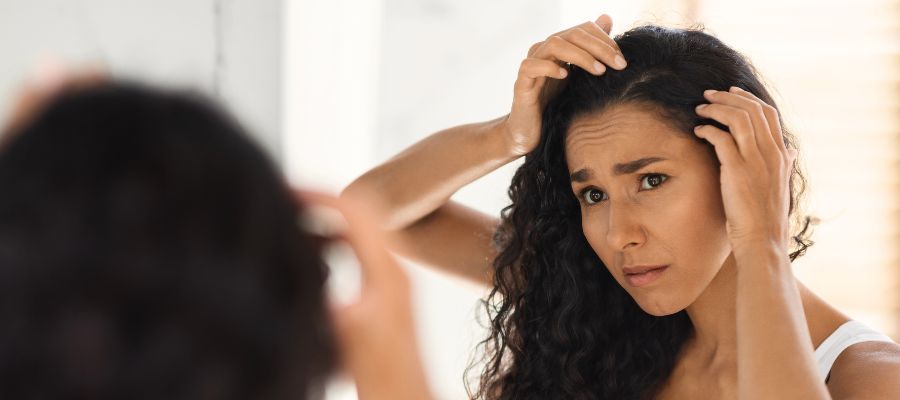 A woman is looking at her hair in the mirror.