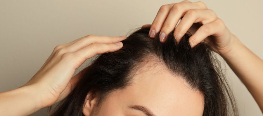 A woman is touching her hair with her hands.