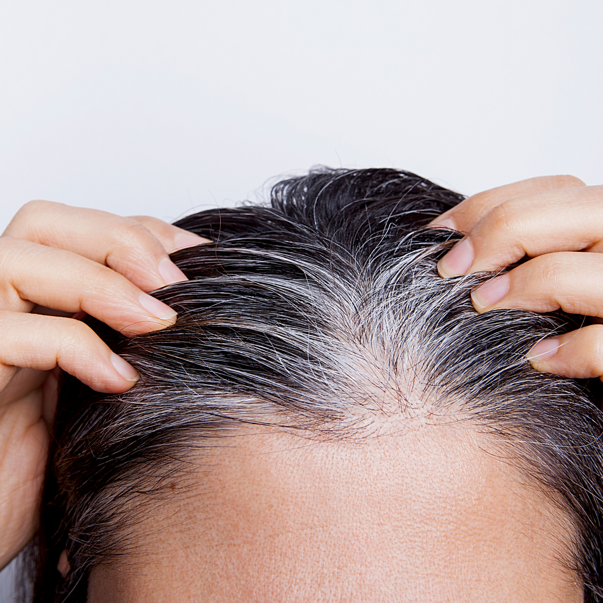 A woman is touching her hair with her hands.