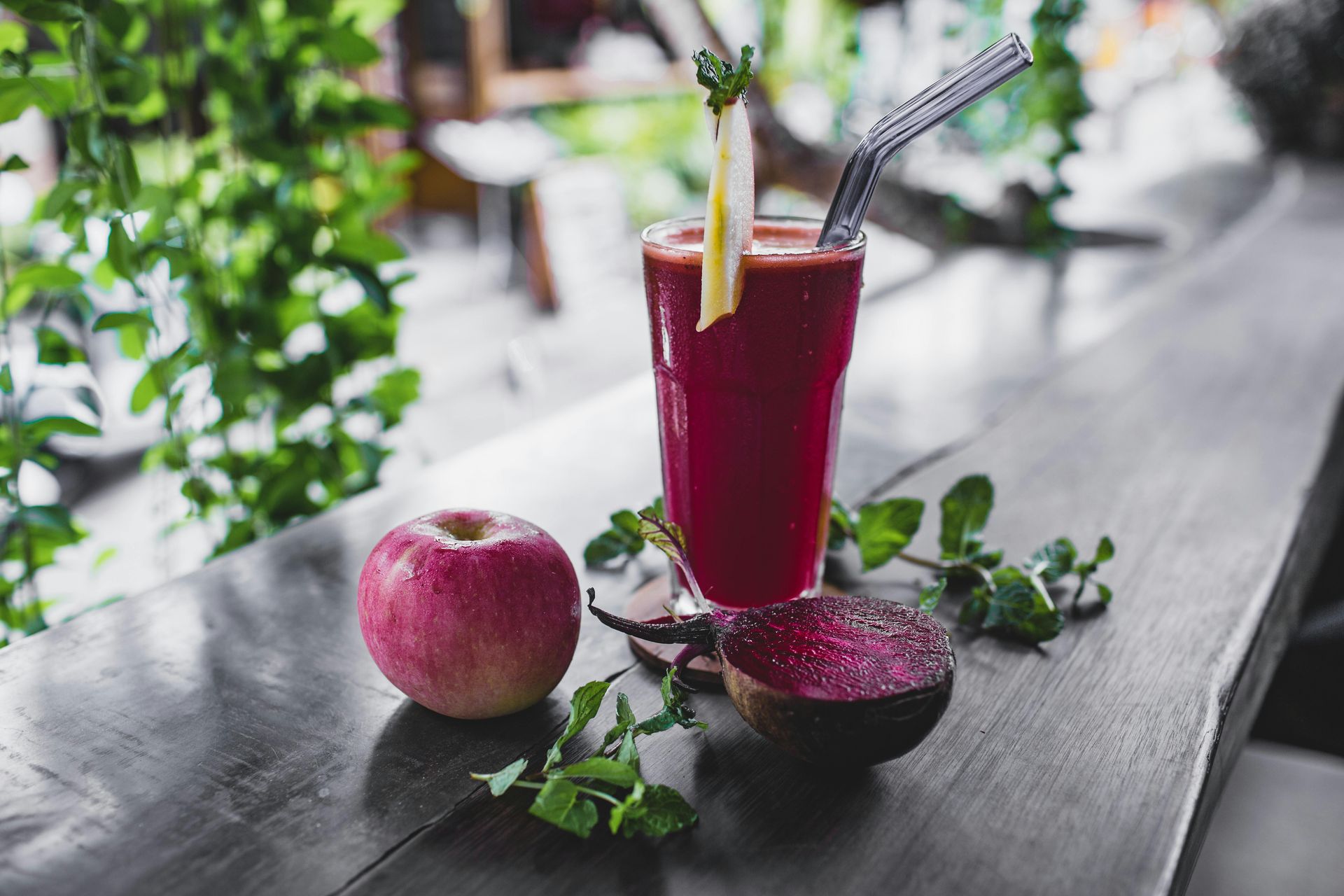 A woman is pouring a green smoothie into a glass.