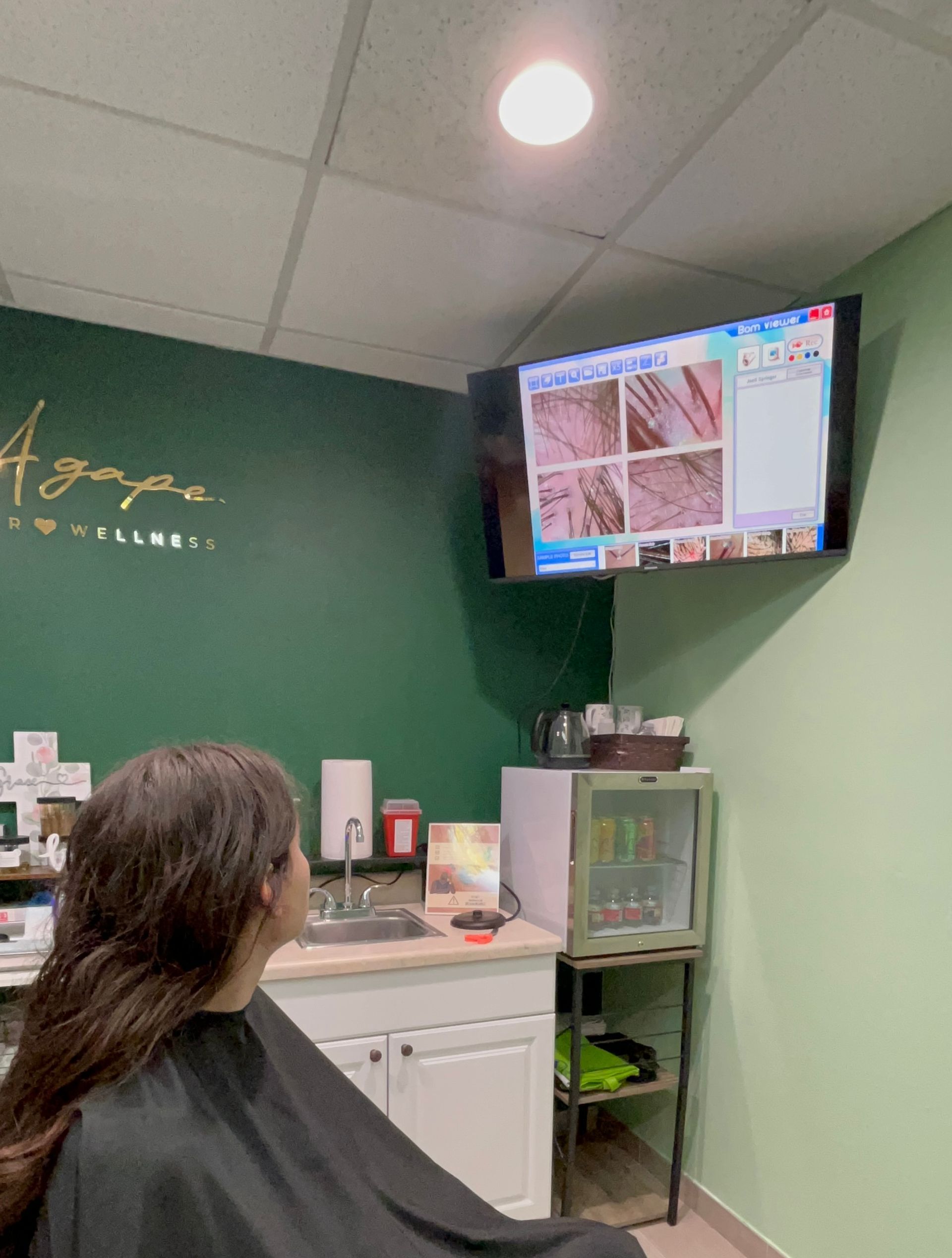 A woman is spraying her hair with a bottle of perfume.