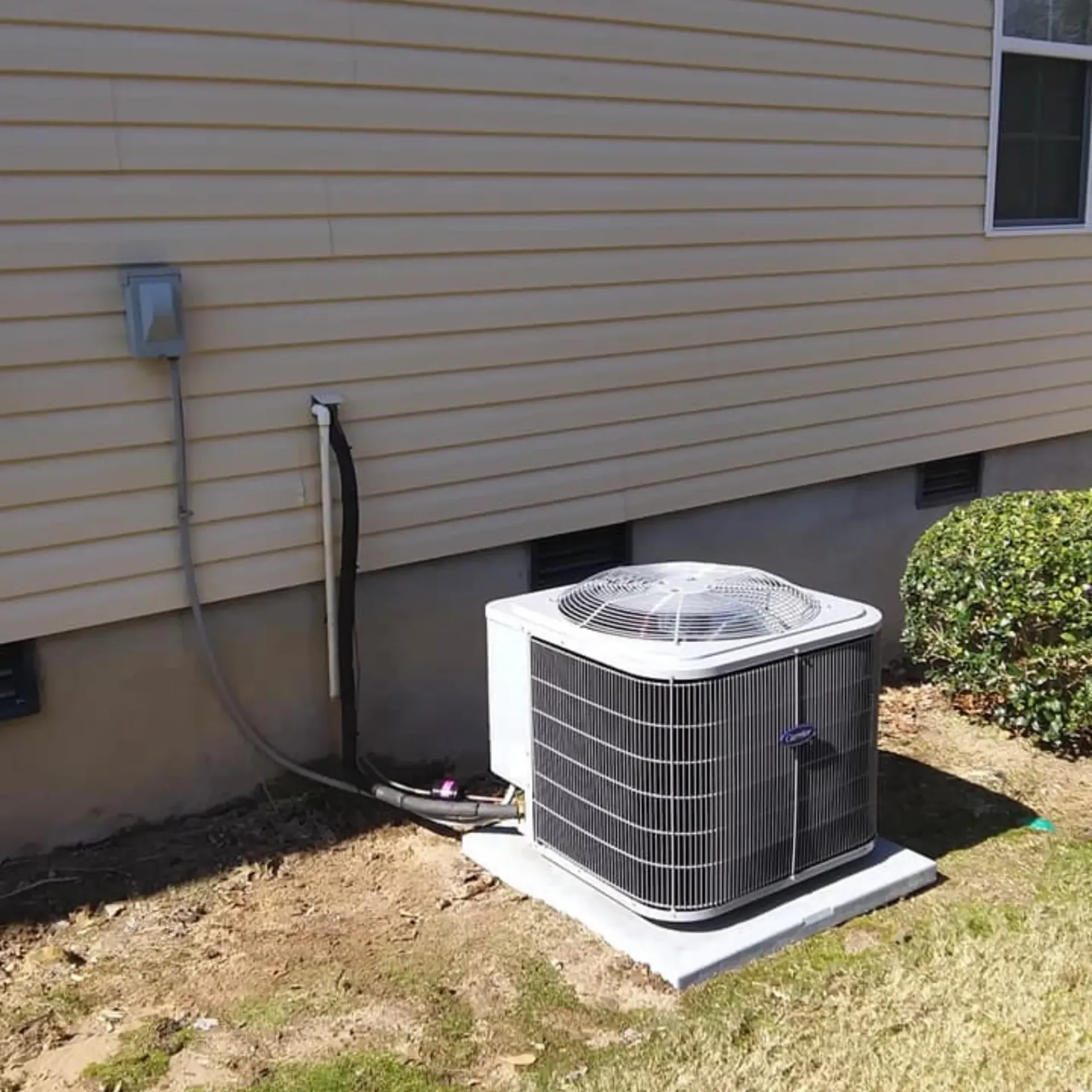 An air conditioner is sitting on the side of a house.