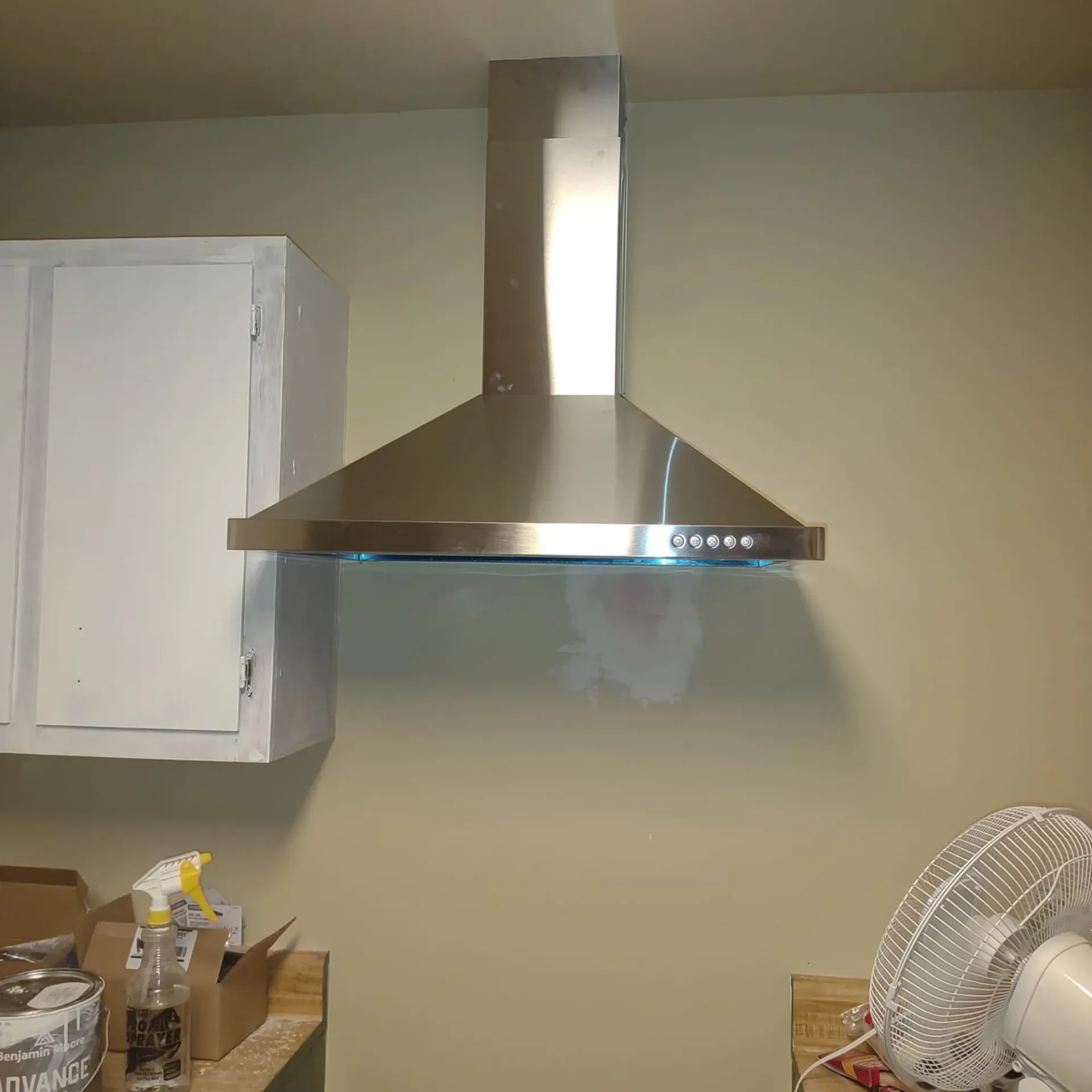 A kitchen with a stainless steel hood and a fan