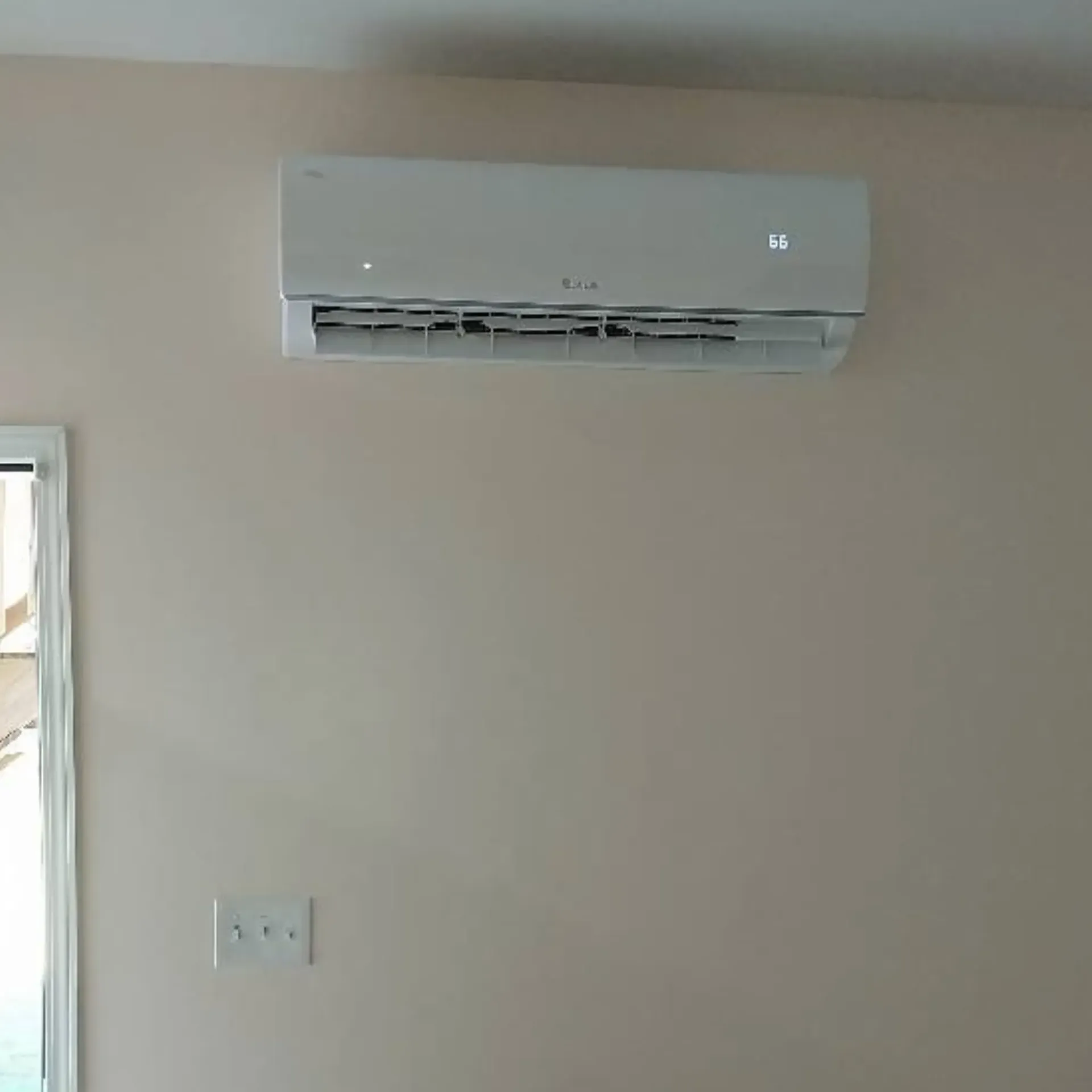 A white air conditioner is hanging on a wall next to a door.