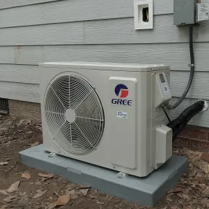 A gree air conditioner is sitting outside of a house.