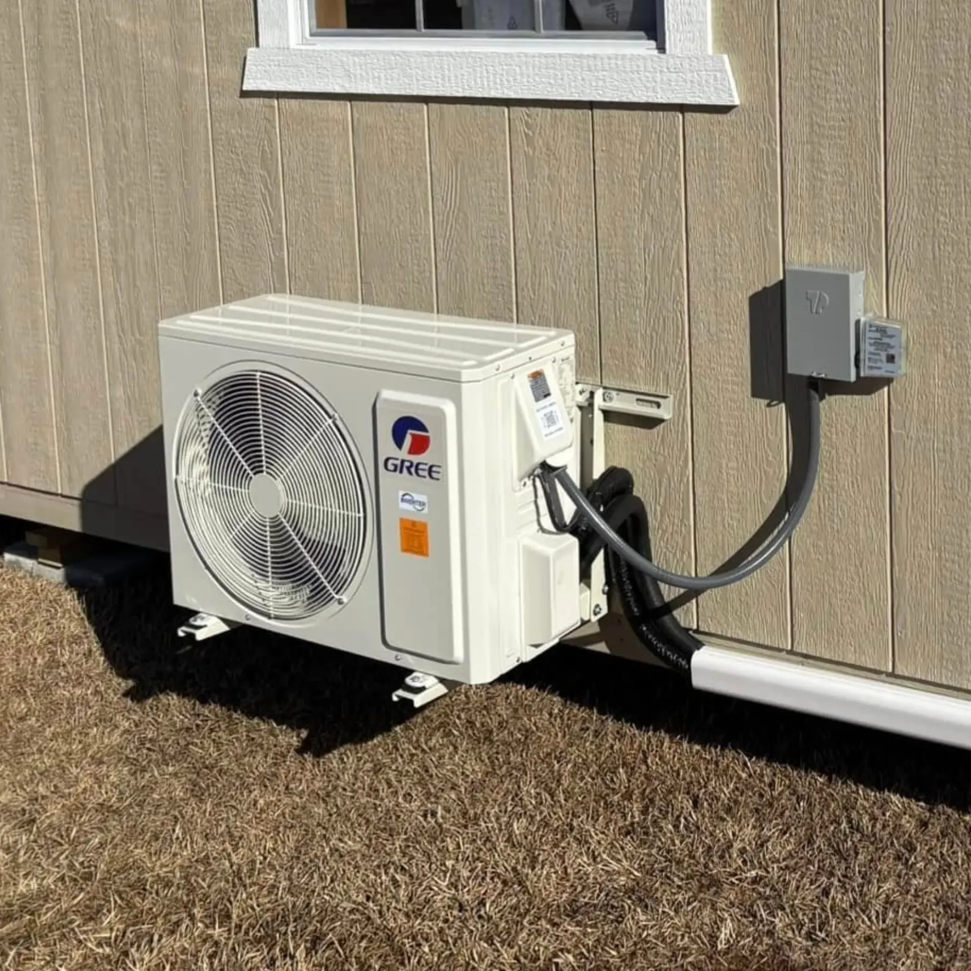 A gree air conditioner is attached to the side of a building.