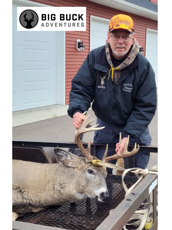 Hunter proudly holding a harvested deer in the woods