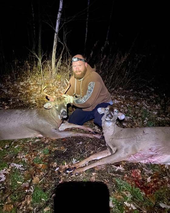 Hunter holding a freshly harvested deer in the snowy forest