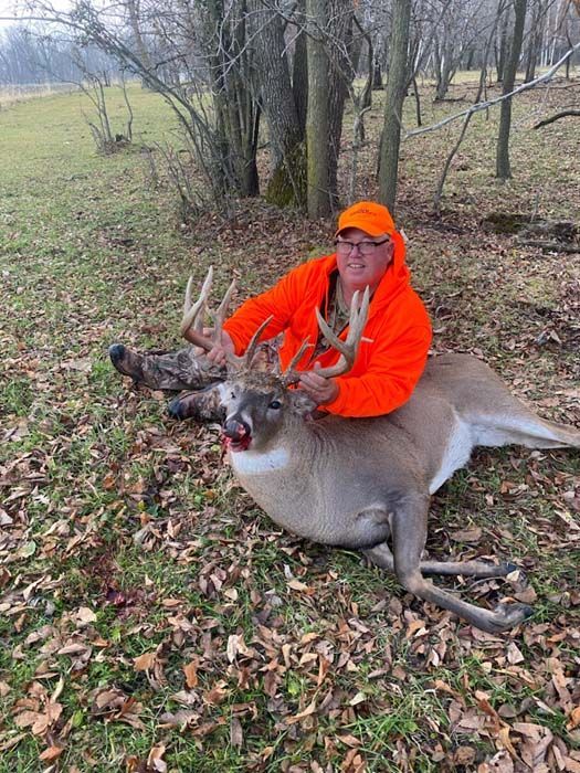 Proud hunter standing next to a large deer after the hunt