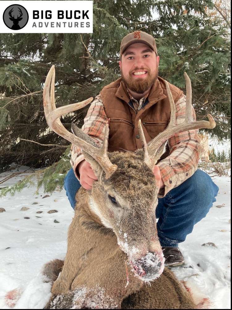 Smiling hunter standing with a deer in his arms