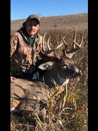 A man is standing next to a large deer in a field.