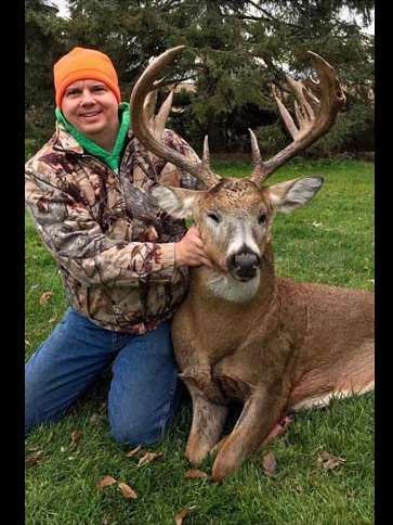 A man is kneeling down next to a large deer in a field.