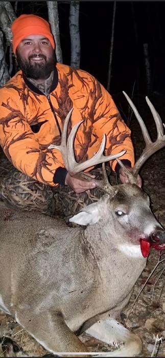 Hunter holding a large antlered deer in the woods