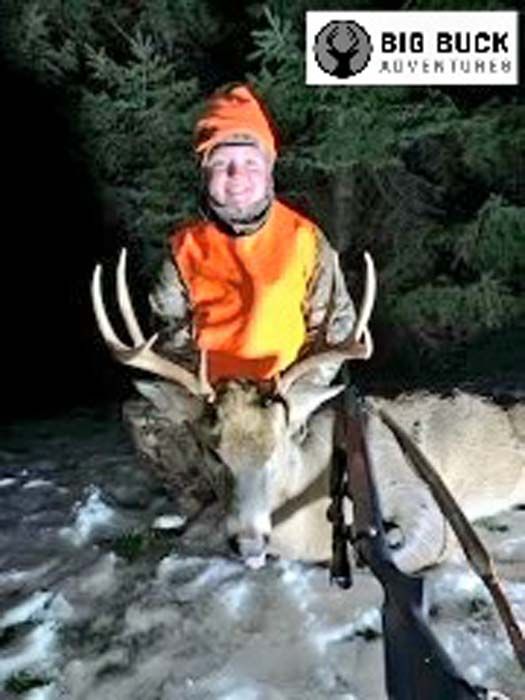 Hunter with a large buck held in his arms after a successful hunt