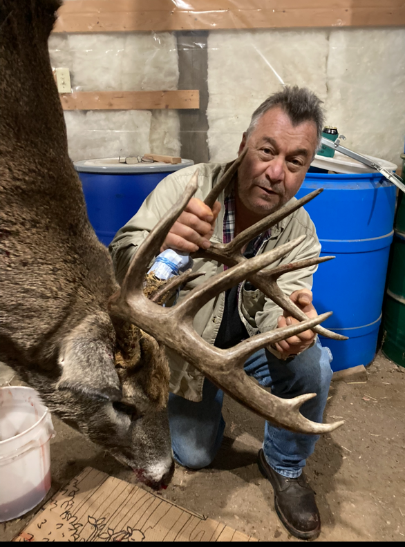 A man is kneeling down next to a large deer
