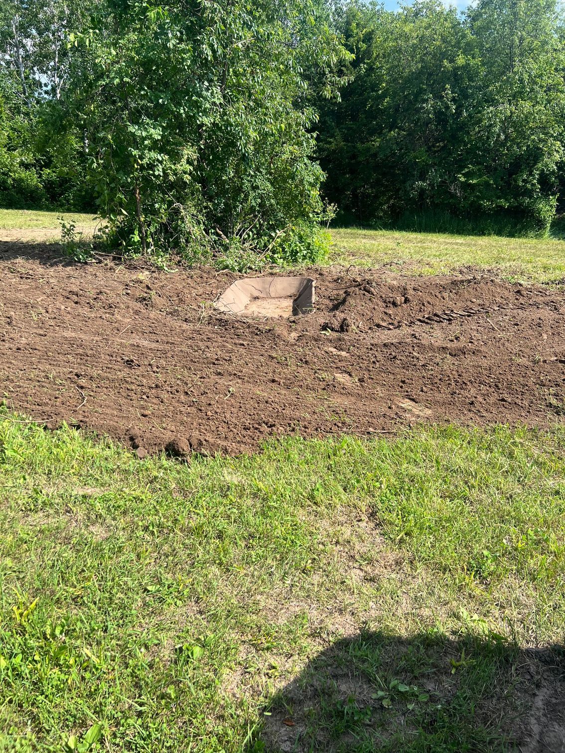 A large pile of dirt is sitting in the middle of a grassy field.