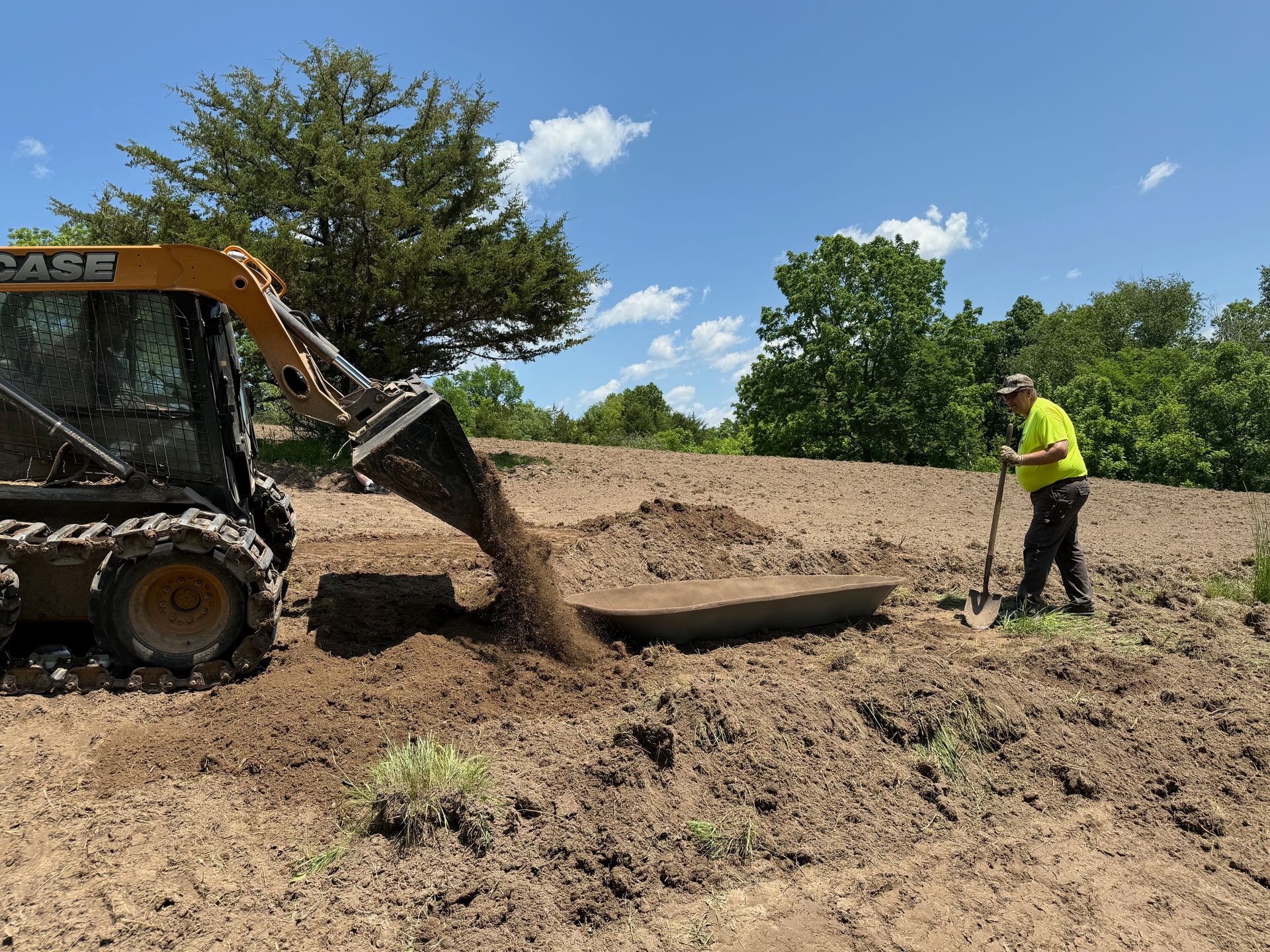 A man is standing in the dirt next to a bulldozer.
