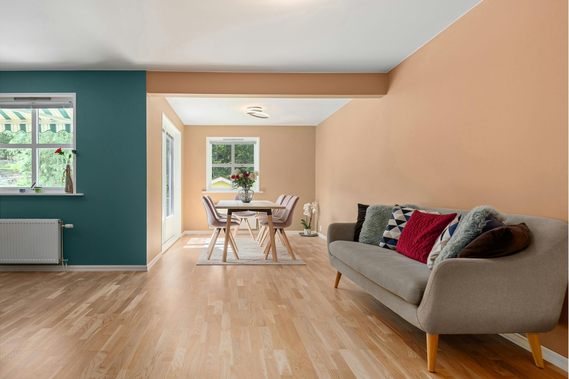 Living room with teal and peach walls, light wood floor, and gray sofa.