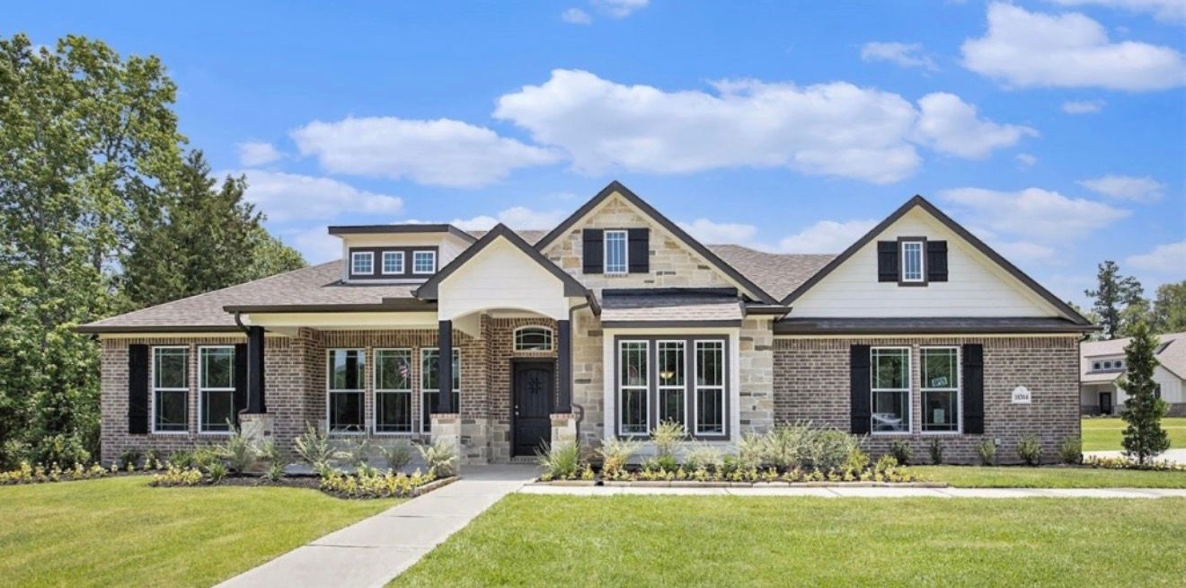 Modern brick house with a white trim and dark shutters, blue sky in the background.