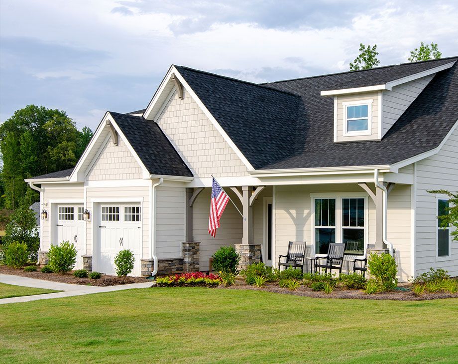 Overhead view of dark gray shingled roofs with a white chimney and a brick walkway in the background.