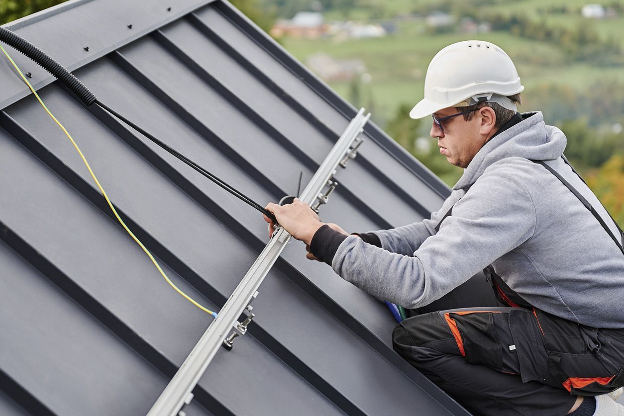 Black roof with matching gutters and downspouts on a house, angled view.
