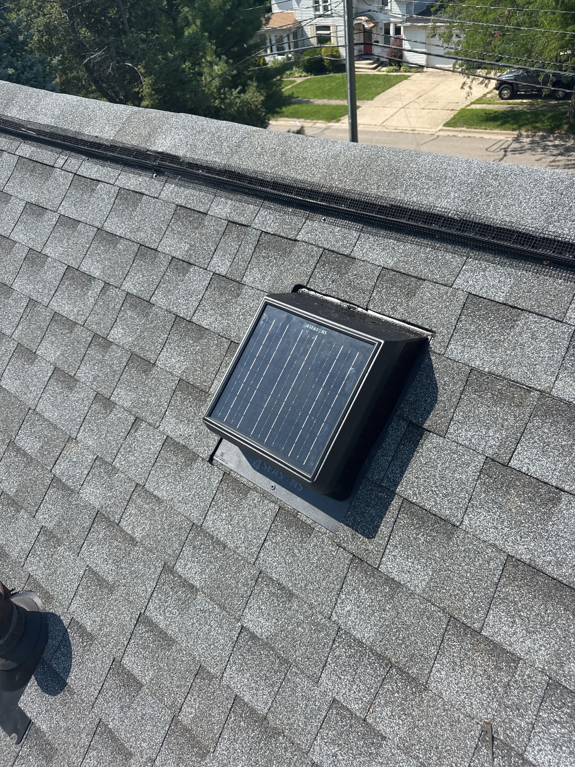 Construction worker installing insulation in an attic with a skylight. He wears a red hard hat and a plaid shirt.