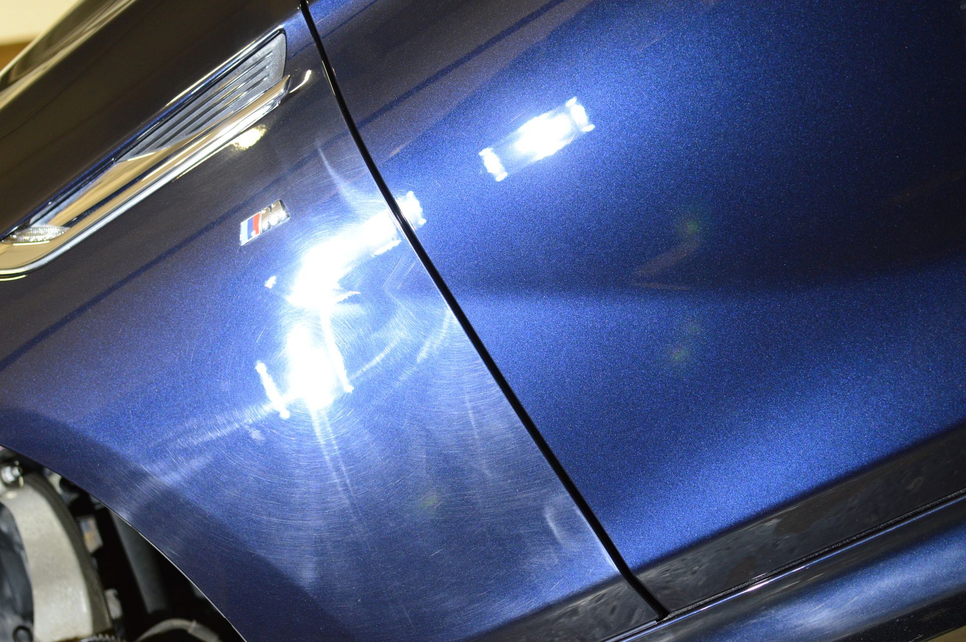 A close up of a blue car with a lot of scratches on it.