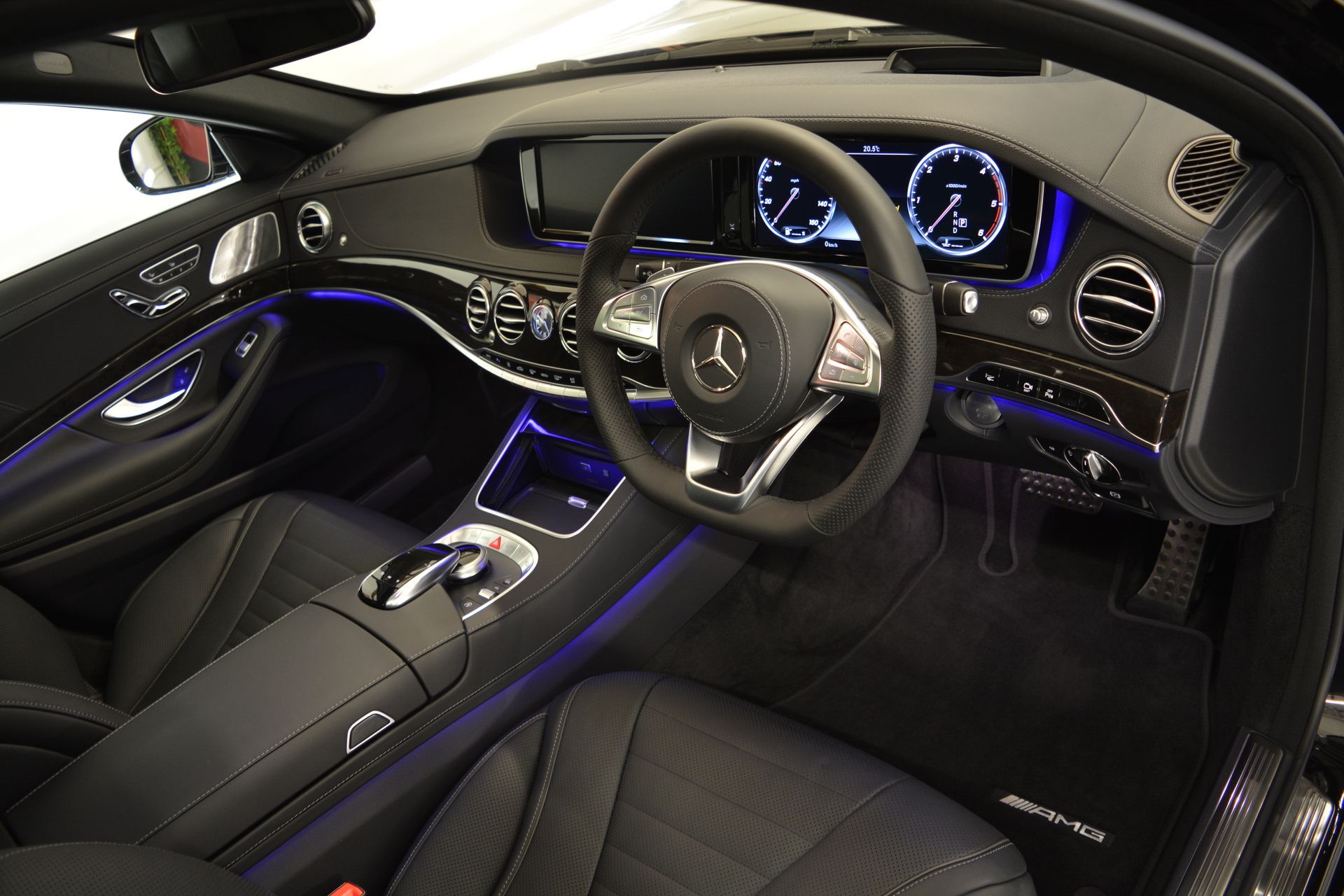 The interior of a black mercedes benz s class with a steering wheel and dashboard.