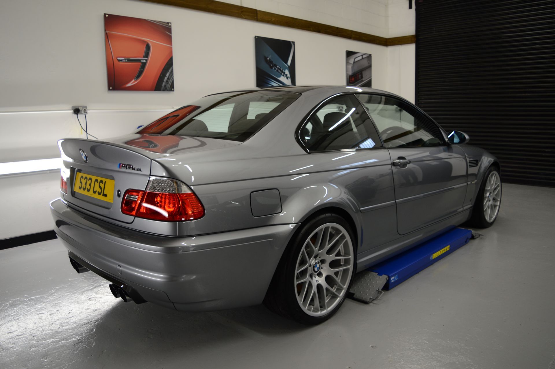 A silver bmw m3 is parked in a garage on a lift.