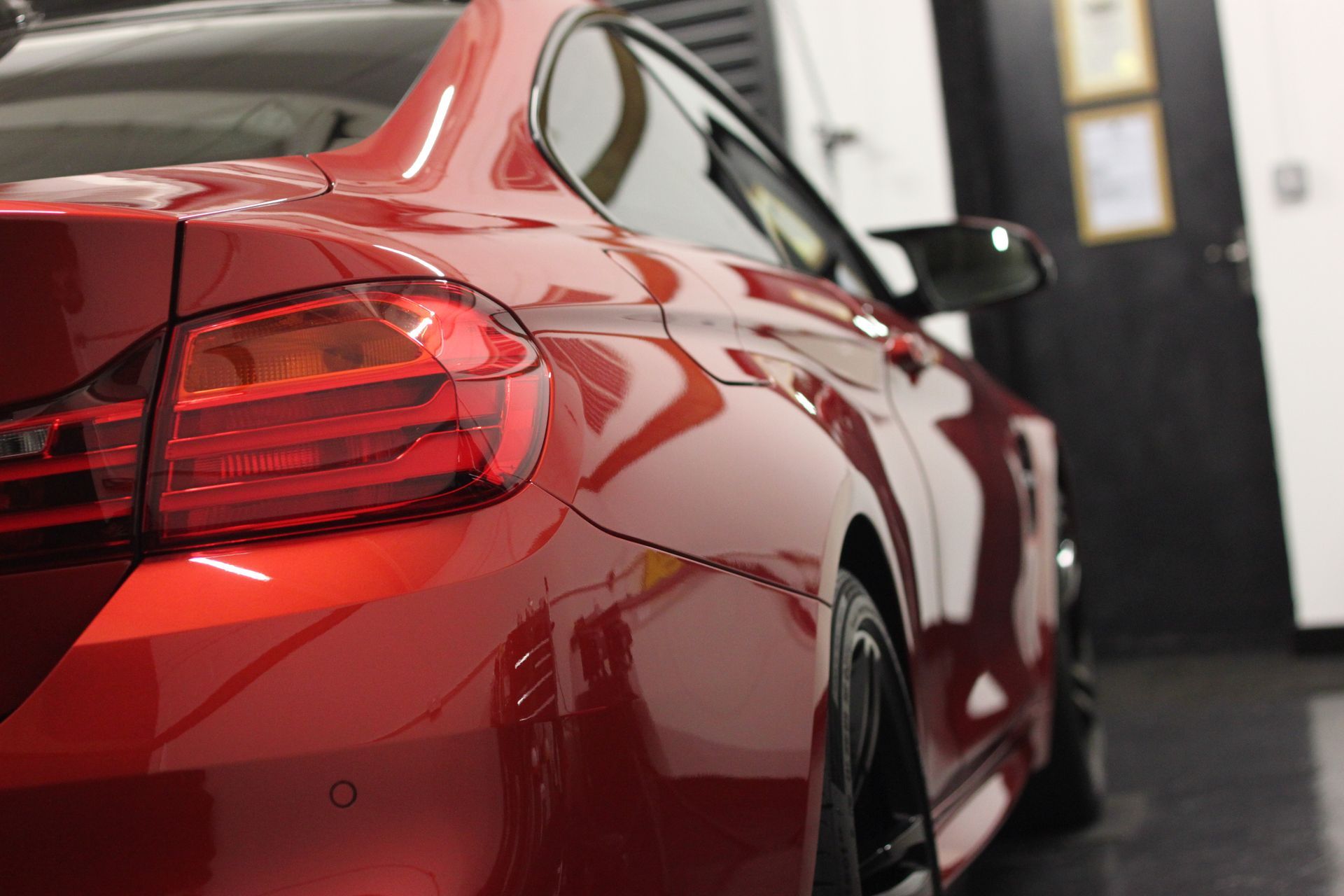 A red car is parked in a garage next to a door.