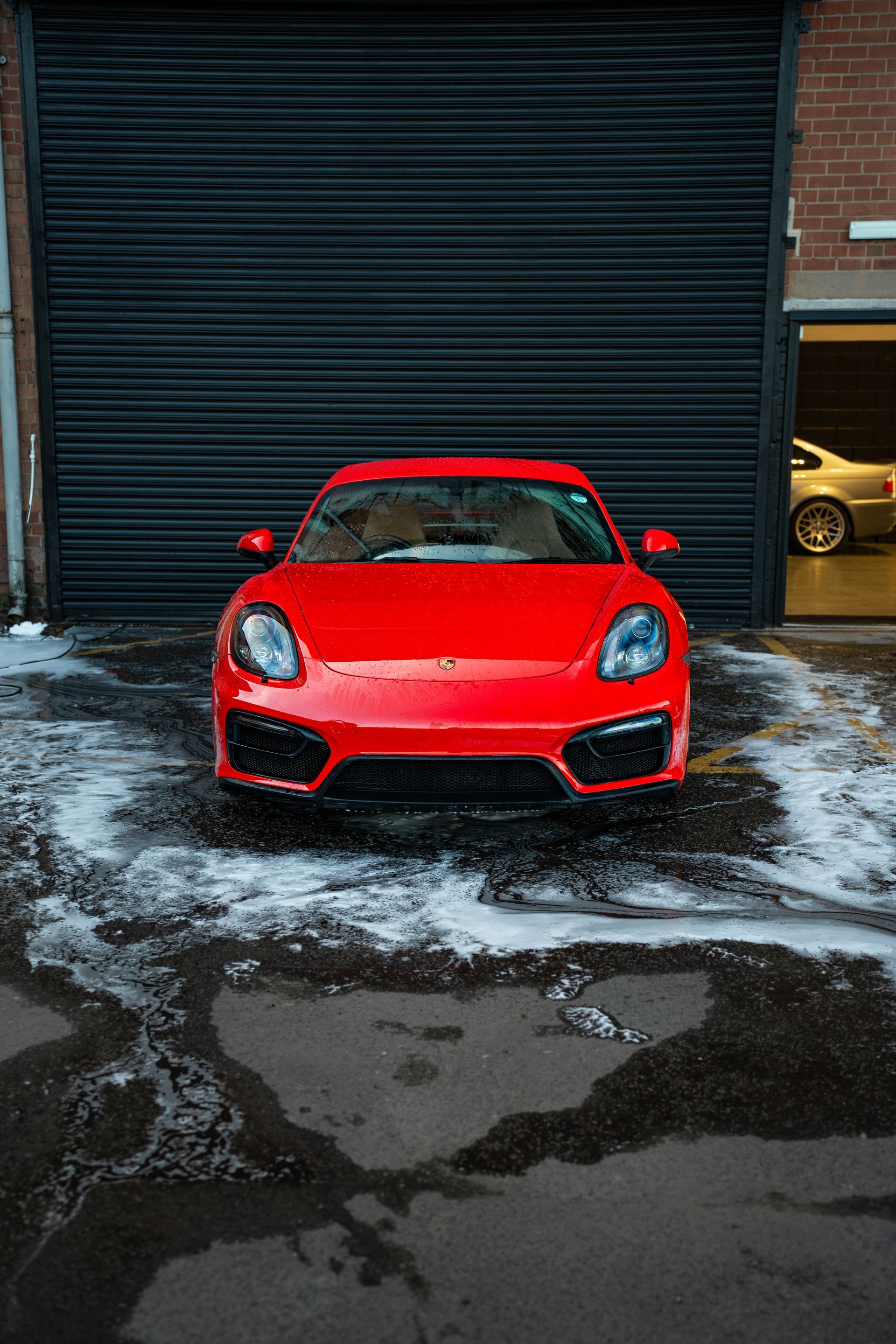 A red sports car is parked in front of a garage door.