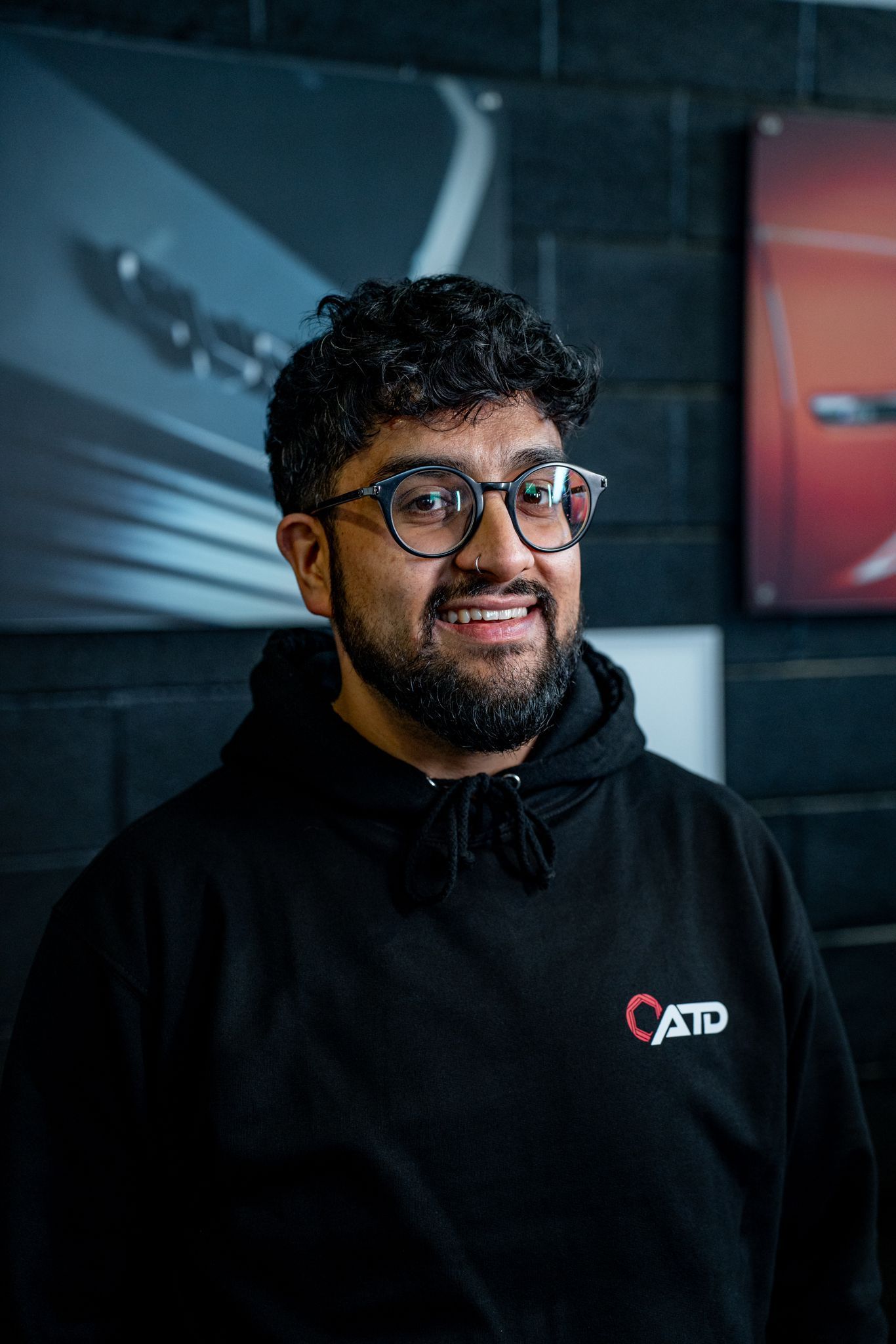 A man with a beard and glasses is wearing a black hoodie.