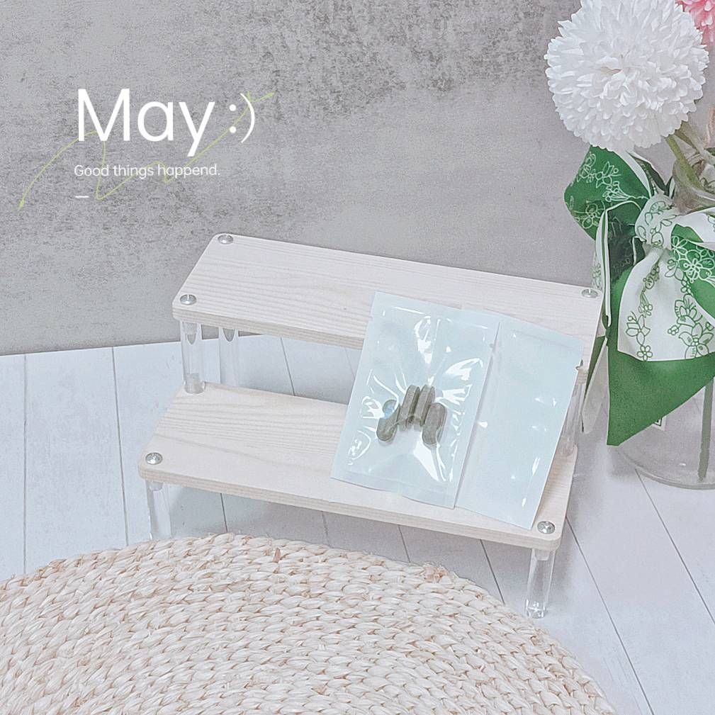 一手拿著一個白色小包，裡面裝著四顆棕色的藥丸狀物品，背景則是一面淺灰色的牆，牆上寫著詩句。