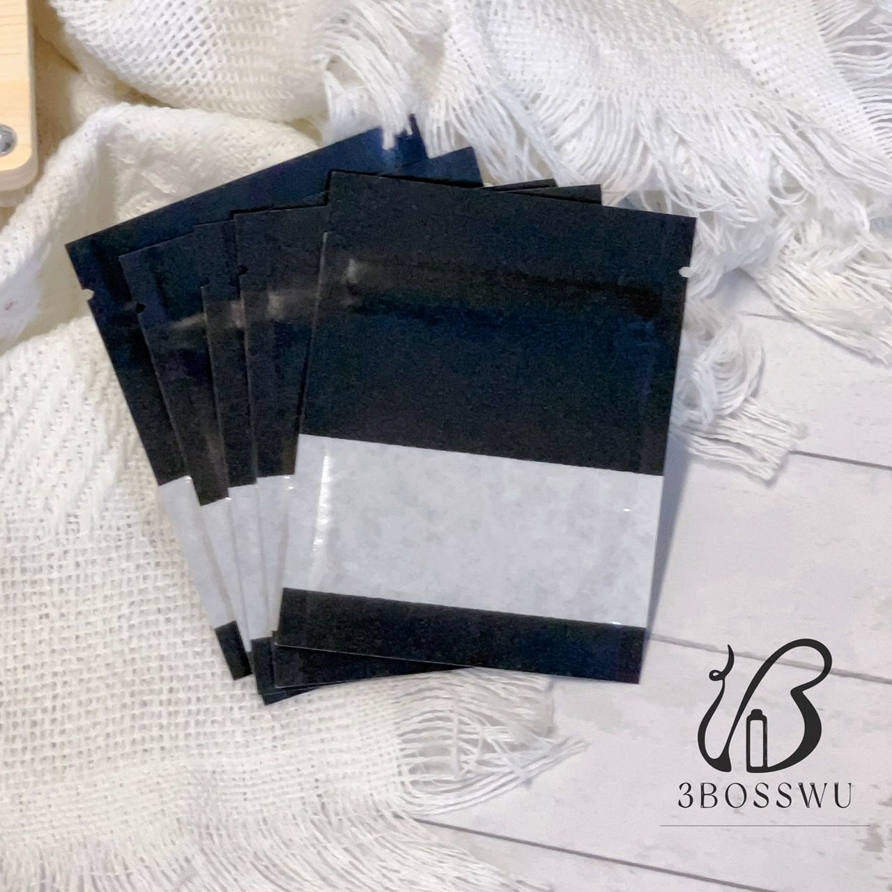 一疊五個帶有透明觀察窗的黑色小密封袋，放在一塊帶流蘇的布上。