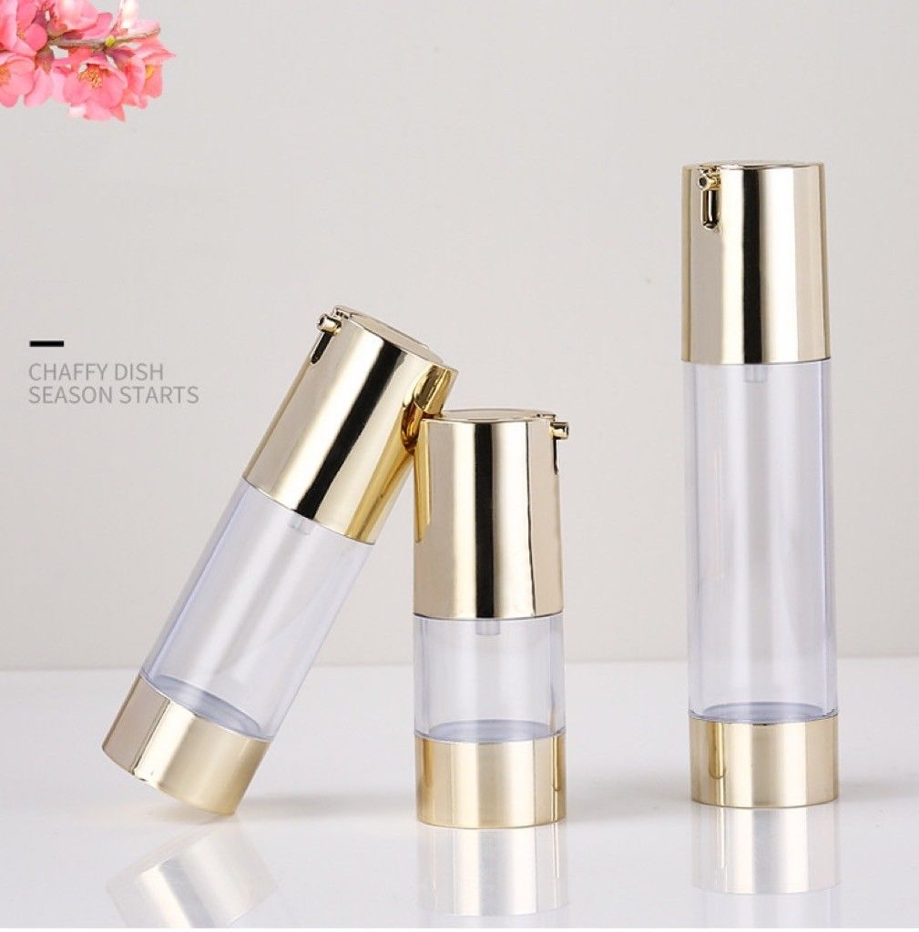 三個空的化妝品真空泵瓶，瓶身透明，瓶蓋和瓶底為金色，擺放在白色表面上。