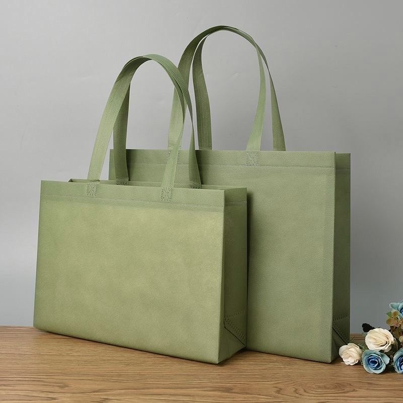 兩個大小不同的長方形深紅色不織布手提袋並排放置在木質表面上。