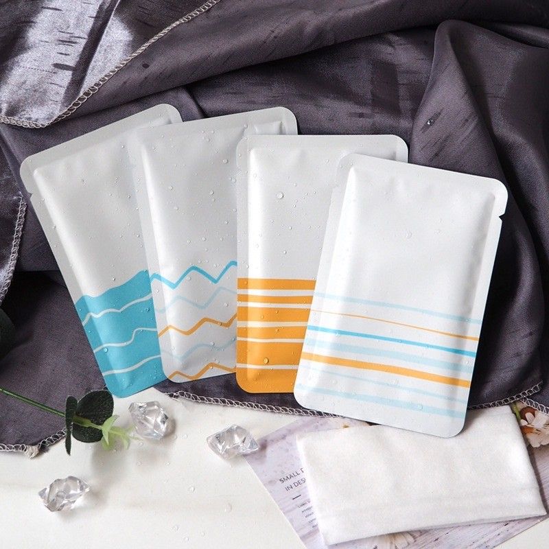 一個長方形的白色護膚品包裝袋，底部有手繪的水平黃色條紋，放在一個底座上。